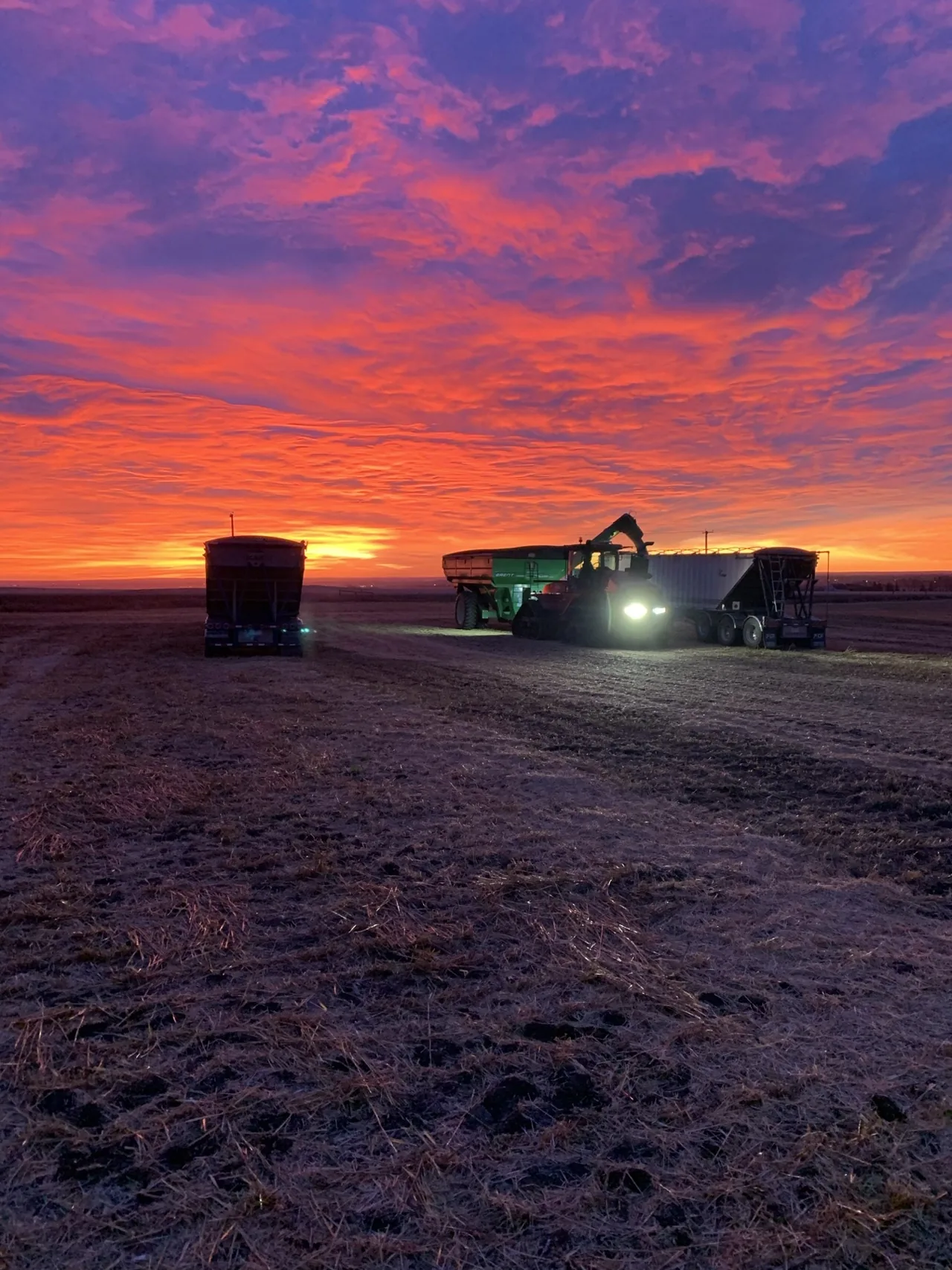 Harvest equipment at rest beneath a vivid Southern Alberta sunset